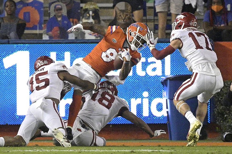 Florida wide receiver Trevon Grimes scores on a 9-yard reception among Arkansas defenders Simeon Blair (15), Myles Mason (18) and Hudson Clark (17) during the first half Saturday in Gainesville, Fla. It was one of five first-half touchdowns for Gators quarterback Kyle Trask, who threw for 356 yards and six touchdowns overall in Florida’s 63-35 victory. More photos at arkansasonline.com/1115razorbacks/
(AP/Phelan M. Ebenhack)