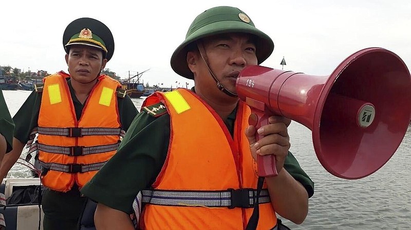 A Vietnamese coast guard officer Saturday warns residents of a fishing boat in Quang Binh province to prepare for typhoon weather. Video at arkansasonline.com/1115vamco/.
(AP/VNA/Nguyen Duc Tho)