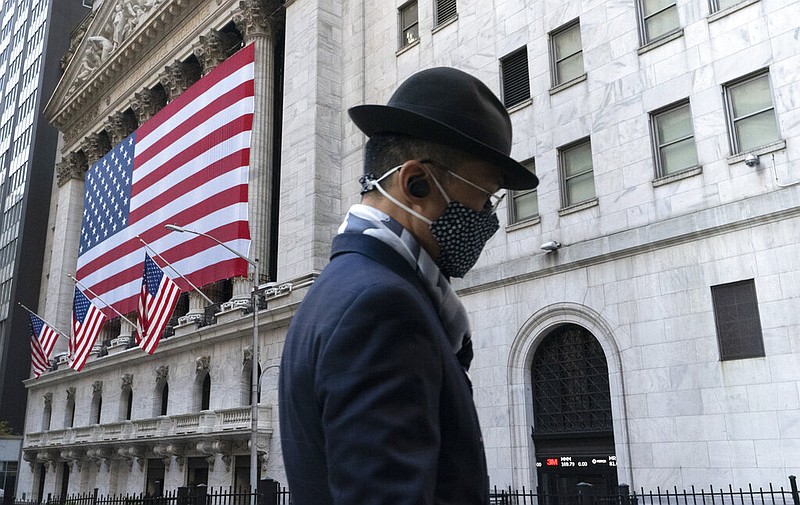 A man wearing a mask passes the New York Stock Exchange, Monday, Nov. 16, 2020, in New York.