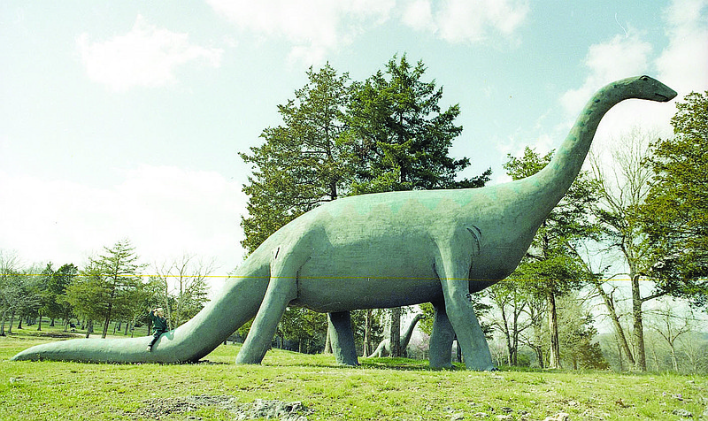 Farwell's Dinosaur Park

In 1967 Emmet Sullivan began work on Farwell's Dinosaur Park near Beaver Dam. It wasn't as much of a stretch for Sullivan as you might think. In 1936 he helped create Dinosaur Park in Rapid City, South Dakota. The Carroll County tourist attraction was a joint project between Sullivan and Ola and Maye Farwell, who provided land for the 60-acre park. When it opened in July 1968, it featured about a dozen dinosaurs spread along a two-mile drive, including a 24-foot high, 50-foot long brontosaurus. Over the years craftsmen added more dinosaurs, along with other critters like skunks, monkeys, mongooses, and a kangaroo. In 1979 the Farwells sold the park to Ken & June Childs who renamed it Land of Kong in the early 1980s, after the addition of a 42-foot tall fiberglass statue of King Kong. To increase Kong’s fearsomeness, he was electrified to allow for a chomping jaw and blinking red lights for eyes. The park closed in 2005. A few years later it was named one of America’s “10 Most Endangered Roadside Places.” Today the dinosaurs live out a lonely life behind their padlocked gate.
(Shiloh Museum of Ozark History/Springdale News Collection)