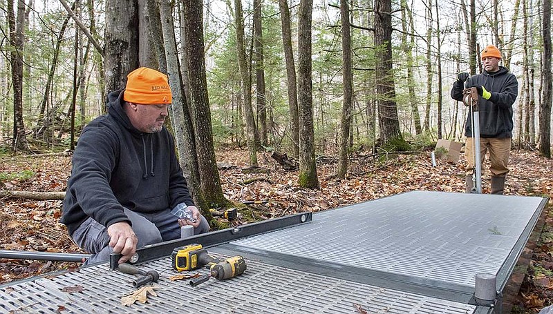 Allied Dock Services owner Jesse Williams levels a new section of an elevated walkway on Monday in the Bragdon Hill Conser- vation Area in Poland, Maine. (AP/Sun Journal/Russ Dillingham) 