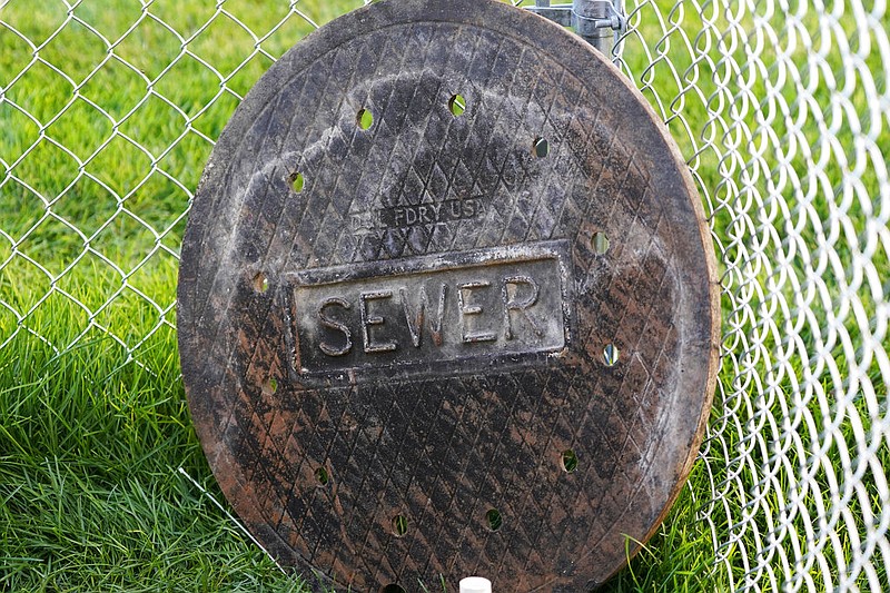 A sewer manhole cover is shown in this Sept. 2, 2020, file photo. Cities and colleges around the country are monitoring wastewater in hopes of stopping coronavirus outbreaks before they get out of hand.