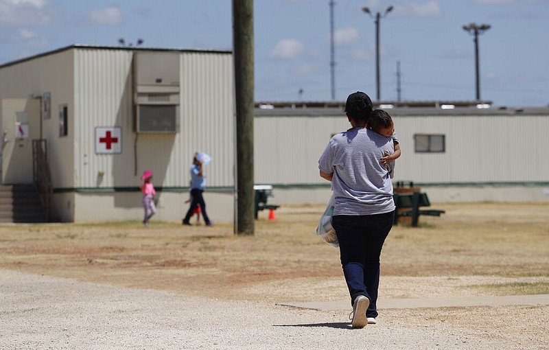 FILE - In this Aug. 23, 2019 file photo, immigrants seeking asylum walk at the ICE South Texas Family Residential Center, in Dilley, Texas.