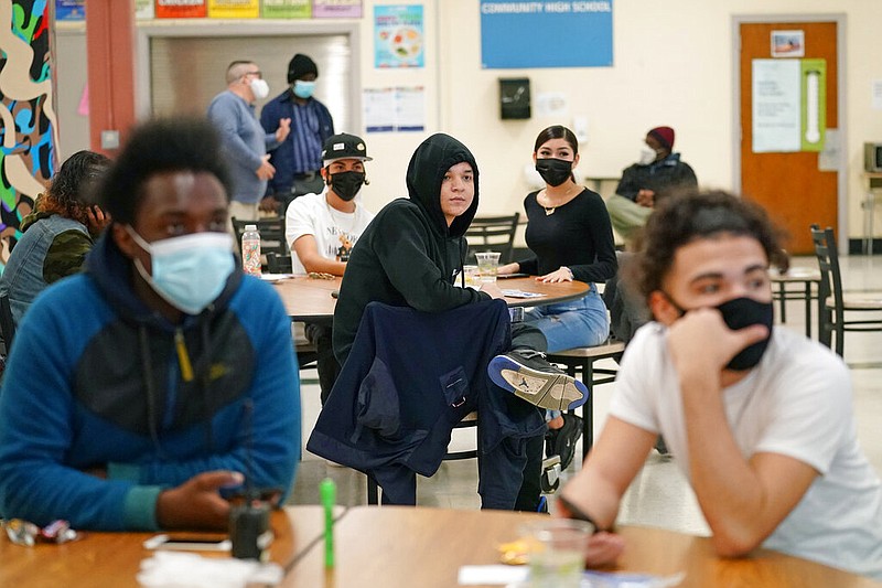 FILE- In this Oct. 29, 2020, file photo, students at West Brooklyn Community High School listen to questions posed by their principal during a current events-trivia quiz and pizza party in the school's cafeteria in New York.