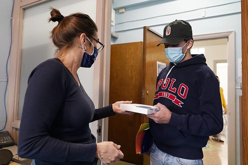 Karen Dette, director of Good Shepherd Services, hands a portable internet hot spot to student Jovanny Mendez at West Brooklyn Community High School in Brooklyn, N.Y., on Wednesday after the school’s principal announced that the school would be closing “until further notice” because of rising cases of the coronavirus in the city. More photos at arkansasonline.com/1119covid/.
(AP/Kathy Willens)