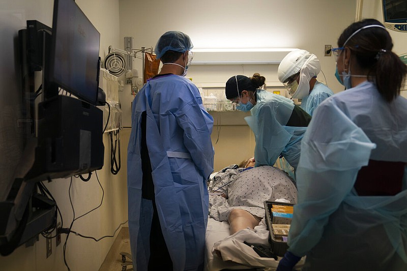FILE - In this Nov. 19, 2020, file photo, EMT Giselle Dorgalli, third from right, performs chest compression on a patient who tested positive for coronavirus in the emergency room at Providence Holy Cross Medical Center in the Mission Hills section of Los Angeles. (AP Photo/Jae C. Hong, File)
story.lead_photo.caption