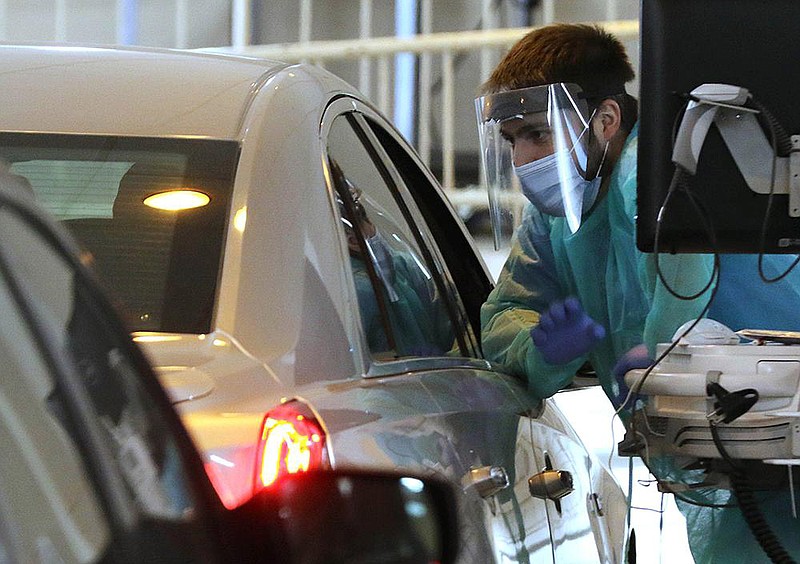 Dr. Caleb Guthrey screens a patient Thursday at the drive-thru covid-19 testing site at the University of Arkansas for Medical Sciences in Little Rock.
(Arkansas Democrat-Gazette/Thomas Metthe)