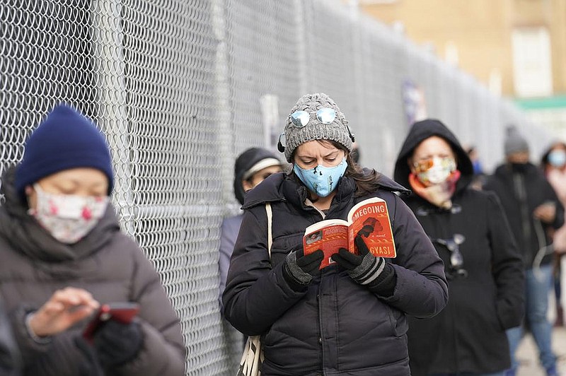 Ashley Gannon reads a book as she and others wait in line Thursday outside a covid-19 testing site in the Brooklyn borough of New York. Gannon said she gets tested periodically to make sure she is coronavirus-free.
(AP/Kathy Willens)