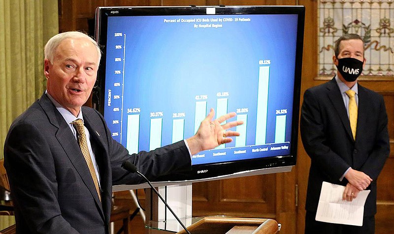 Gov. Asa Hutchinson discusses a chart showing the percentage of intensive-care beds used by covid-19 patients. He was joined by Dr. Cam Patterson, chancellor of the University of Arkansas for Medical Sciences, for Friday’s coronavirus briefing at the Capitol. More photos at www.arkansasonline.com/1121covid/.
(Arkansas Democrat-Gazette/Thomas Metthe)