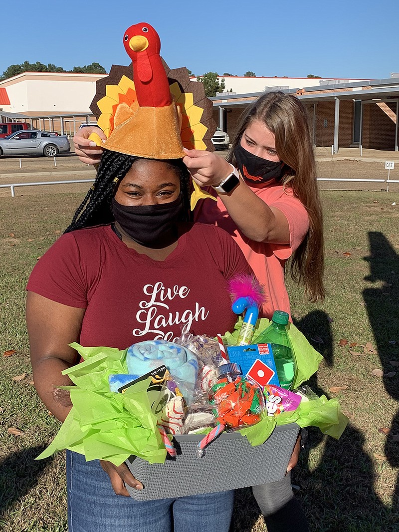 Natalie Boyd helps JaNay Cross try on her prize turkey hat. Cross gave a 12-foot inflatable turkey its winning name.