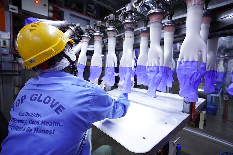 In this Wednesday, Aug. 26, 2020, file photo, a worker inspects disposable gloves at the Top Glove factory in Shah Alam on the outskirts of Kuala Lumpur, Malaysia.
