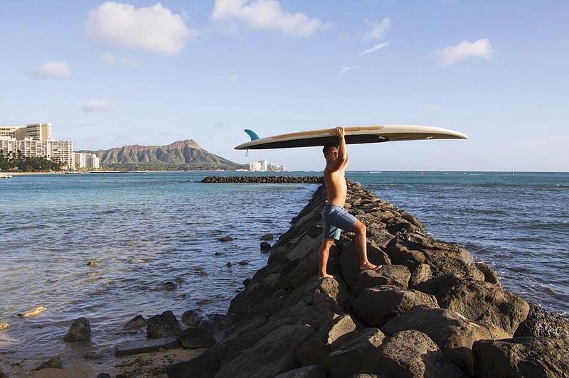 Bryant de Venecia stands at the ocean with his paddleboard Wednesday in Honolulu. Valencia says he has “messy” feelings about Hawaii’s pause in tourist crowds since many members of his union lost paychecks and medical coverage. More photos at arkansasonline.com/1127hawaii.
(AP/Courtesy of Yoko Liriano)