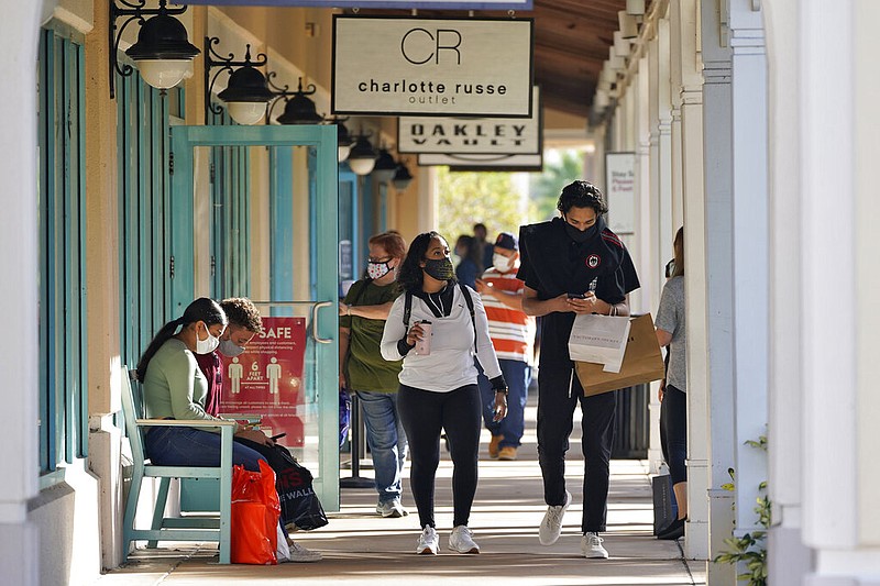 Shoppers wear protective face masks as they look for Black Friday deals at the Ellenton Premium Outlet stores Friday, Nov. 27, 2020, in Ellenton, Fla.