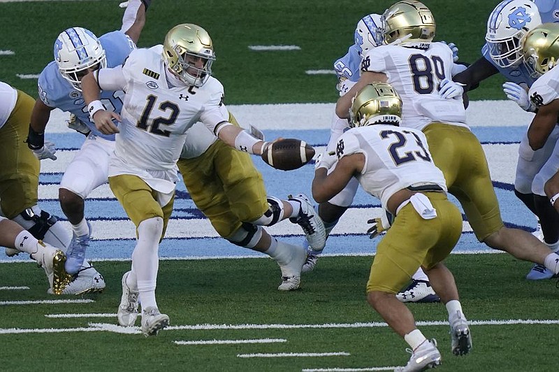 Notre Dame quarterback Ian Book (left) hands off to running back Kyren Williams during the first half Friday against North Carolina in Chapel Hill, N.C. Book threw for 279 yards and a score, and used his mobility and elusiveness to keep plays alive to lead the Irish to a 31-17 victory.
(AP/Gerry Broome)