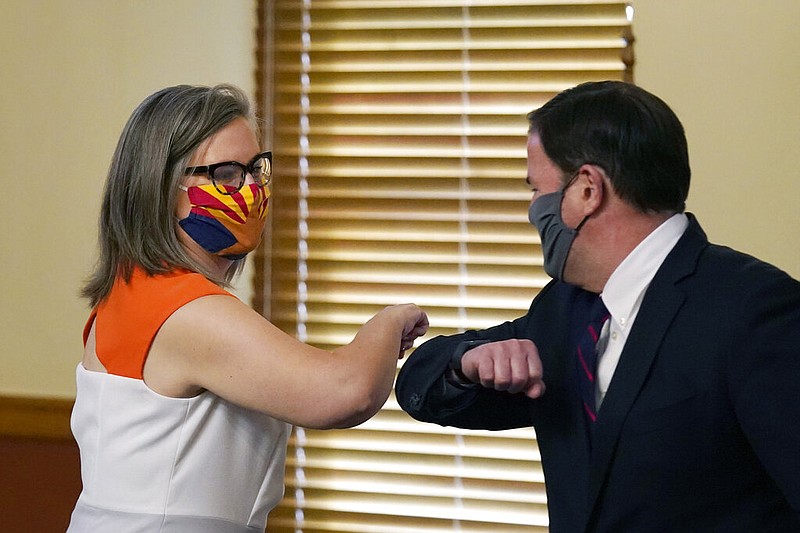 Arizona Secretary of State Katie Hobbs, left, and Arizona Gov. Doug Ducey bump elbows as they meet to certify the election results for federal, statewide, and legislative offices and statewide ballot measures at the official canvass at the Arizona Capitol Monday, Nov. 30, 2020, in Phoenix. (AP Photo/Ross D. Franklin, Pool)

