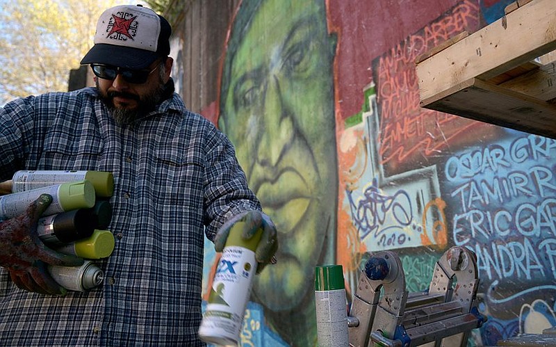 Jose Hernandez packs up his paints at the 7th Street mural on Monday, Nov. 30, 2020 after repairing a part of the mural that was defaced by white paint over the weekend. The faces of George Floyd and Martin Luther King, Jr. were splattered with white paint some time on Saturday.

(Arkansas Democrat-Gazette/Stephen Swofford)