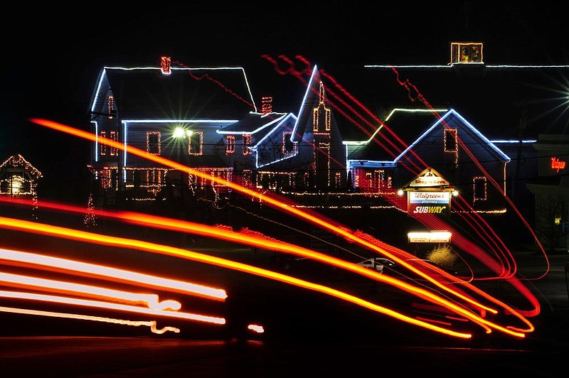 In this image taken with a slow shutter speed, early morning traffic leaves streaks of light as it passes the Naples Barn, an antique and gift shop outlined with holiday lights, Monday, Nov. 30, 2020, in Naples, Maine. Brick and mortar shops like the Naples Barn will be competing with online stores as shoppers look holiday gifts on Cyber Monday. (AP Photo/Robert F. Bukaty)