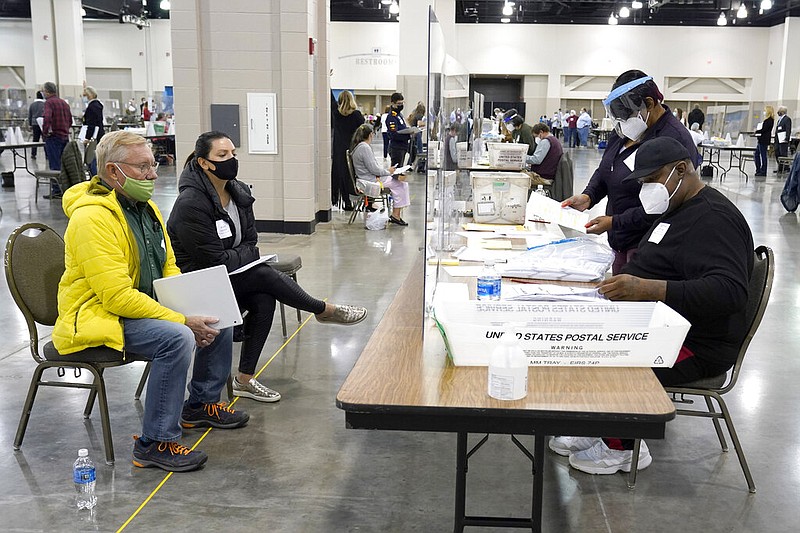 FILE - In this Nov. 20, 2020, file photo, election workers, right, verify ballots as recount observers, left, watch during a Milwaukee hand recount of presidential votes at the Wisconsin Center in Milwaukee.