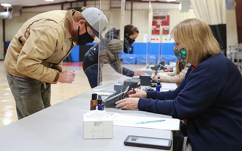 Daniel Smith (left) is assisted by Sarah Harrison, a Washington County election official, a he picks up his ballot to vote during a runoff election Tuesday, Dec. 1, 2020, at the Yvonne Richardson Center in Fayetteville. In Fayetteville, D‚ÄôAndre Jones and Tanner Pettigrew are vying for the open Ward 1, Position 2 seat on the city council. Check out nwaonline.com/201202Daily/ and nwadg.com/photos for a photo gallery.
(NWA Democrat-Gazette/David Gottschalk)