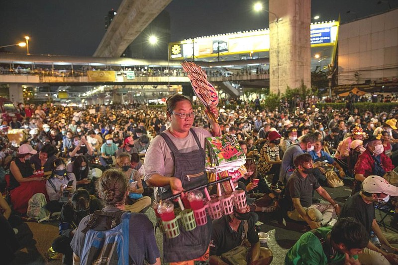 A street vendor sells soft drinks during an anti-government protesters rally on Wednesday, Dec. 2, 2020 in Bangkok, Thailand. Thailand's highest court Wednesday acquitted Prime Minister Prayuth Chan-ocha of breaching ethics clauses in the country's constitution, allowing him to stay in his job. (AP Photo/Gemunu Amarasinghe)