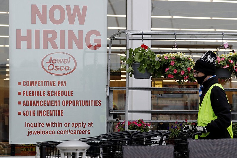 A man pushes carts as a hiring sign shows at a Jewel Osco grocery store in Deerfield, Ill., Thursday, April 23, 2020.