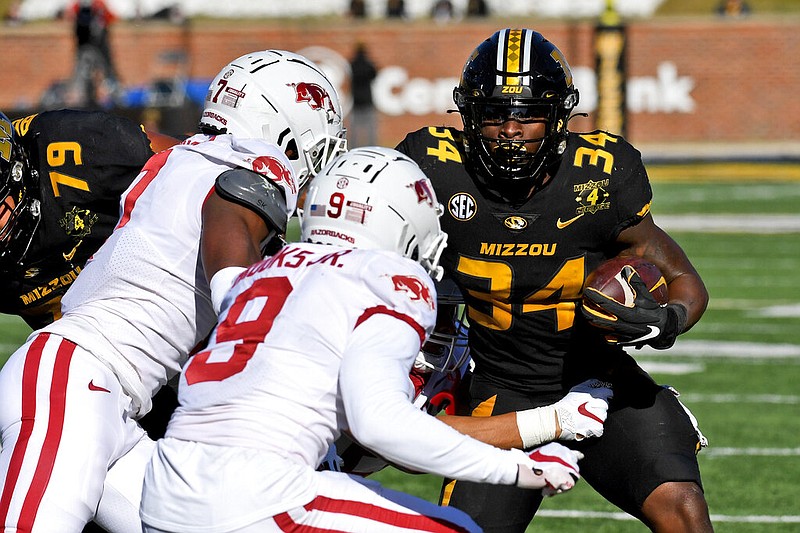 Missouri running back Larry Rountree III (34) runs with the ball as Arkansas defensive back Joe Foucha (7) and defensive back Greg Brooks Jr. (9) defend during the first half in Columbia, Mo., on Saturday, Dec. 5, 2020. (AP Photo/L.G. Patterson)