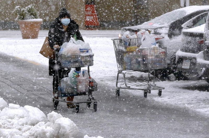 A shopper pushes a full grocery cart through heavy snow Saturday in a parking lot in Marlborough, Mass.
(AP/Bill Sikes)
