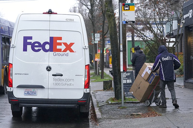 A driver with FedEx carries a package away from a van, Tuesday, Dec. 8, 2020, in Seattle.