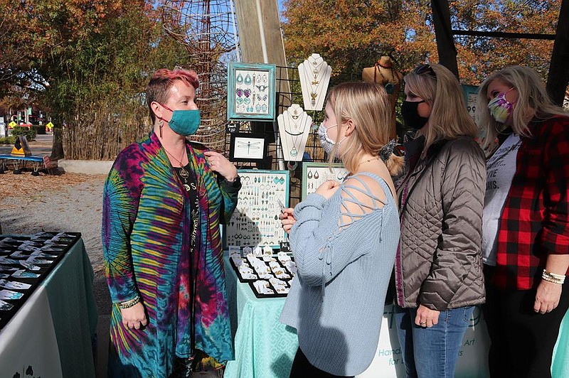 Laura Wilson with Artful Logic shows her wares to Zoe Harrington, Jennifer Harrington and Allison Brockinton of Fayetteville at the Bernice Art Bazaar and Art Party, Nov. 28 (Small Business Saturday) at Bernice Garden. A handful of local artists showed and sold their work.
(Arkansas Democrat-Gazette -- Helaine R. Williams)