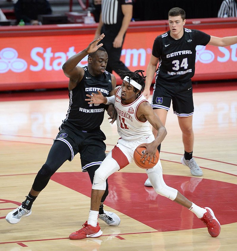 Arkansas guard Jalen Tate (11) drives to the basket Saturday, Dec. 12, 2020, as he is pressured by Central Arkansas forward Eddy Kayouloud (left) during the first half of play in Bud Walton Arena in Fayetteville. Visit nwaonline.com/201213Daily/ for today's photo gallery. 
(NWA Democrat-Gazette/Andy Shupe)