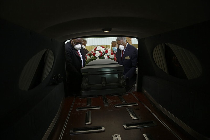 FILE - In this Saturday, April 18, 2020 file photo, mortician Cordarial O. Holloway, foreground left, funeral director Robert L. Albritten, foreground right, and funeral attendants Eddie Keith, background left, and Ronald Costello place a casket into a hearse in Dawson, Ga.