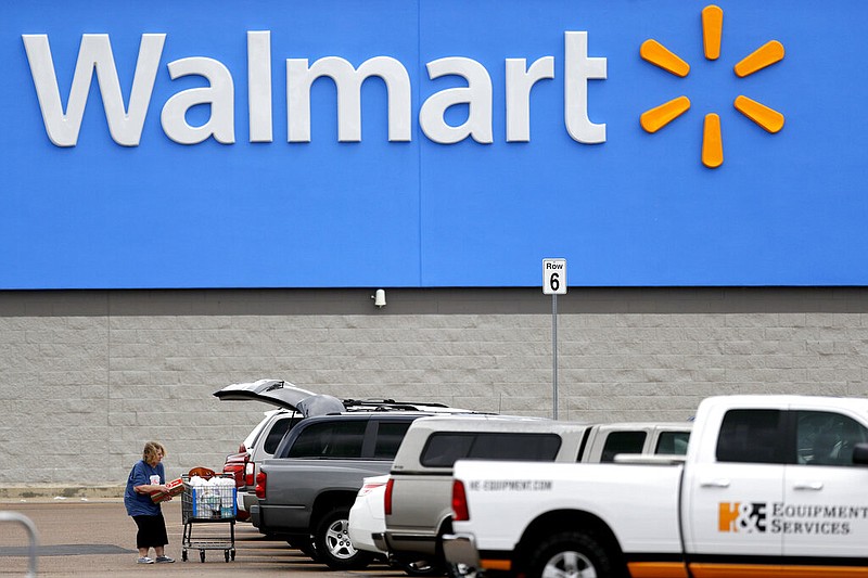 FILE - In this March 31, 2020 file photo, a woman pulls groceries from a cart to her vehicle outside of a Walmart store in Pearl, Miss. Walmart is teaming with the General Motors' Cruise autonomous vehicle unit to test automated package delivery in Arizona. (AP Photo/Julio Cortez, File)