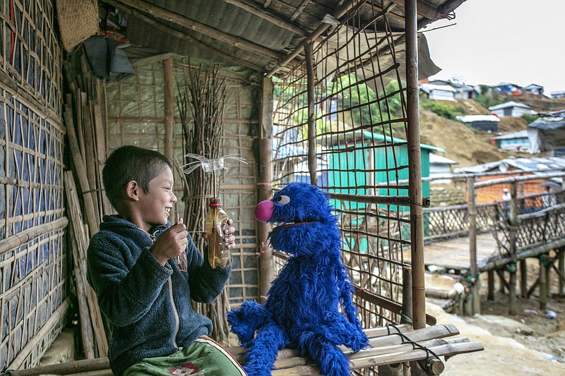 A child in a Rohingya refugee camp visits with Grover the Muppet in Cox’s Bazar, Bangladesh, in a 2018 file photo. Sesame Workshop has unveiled Noor and Aziz, Rohingya Muppets who will feature in educational programming that will be shown in refugee camps. (Ryan Donnell/Sesame Workshop via The New York Times)