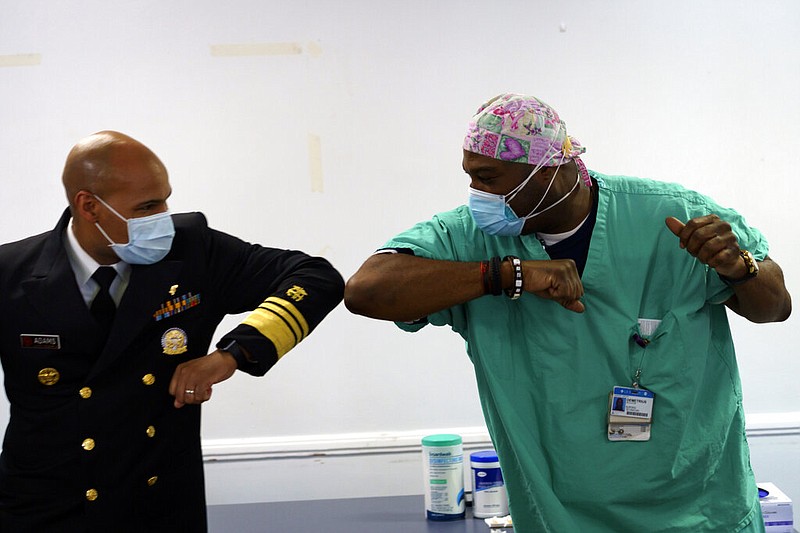 Surgeon General of the U.S. Jerome Adams, left, elbow-bumps Emergency Room technician Demetrius Mcalister after Mcalister got the Pfizer covid-19 vaccination at Saint Anthony Hospital in Chicago, on Tuesday, Dec. 22, 2020.