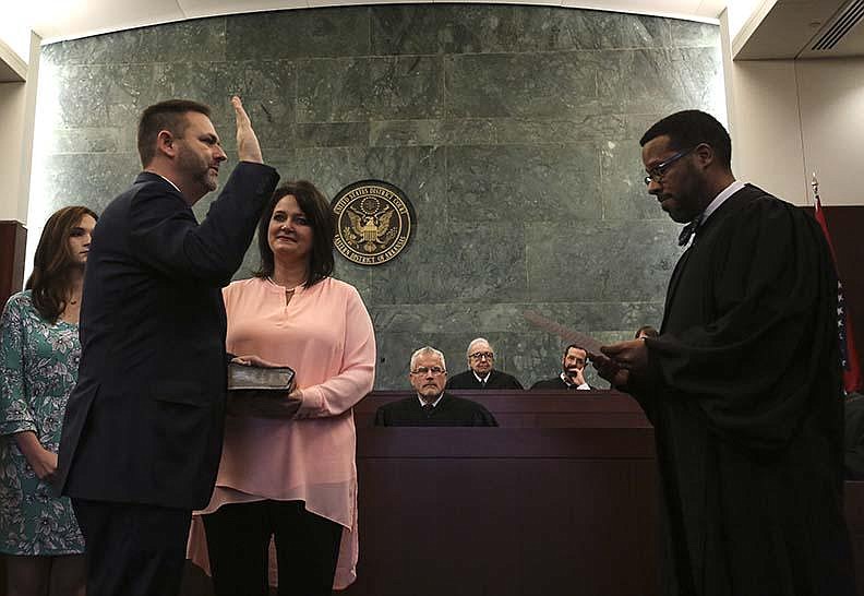 Cody Hiland holds his hand on a Bible held by his wife, Jana, as he takes the oath of office to become U.S. attorney for the Eastern District of Arkansas in a Jan. 26 ceremony administered by U.S. District Judge Brian S. Miller. Hiland announced Thursday that he is resigning at the end of the year. More photos at arkansasonline.com/1225hiland/.
(Arkansas Democrat-Gazette/Thomas Metthe)