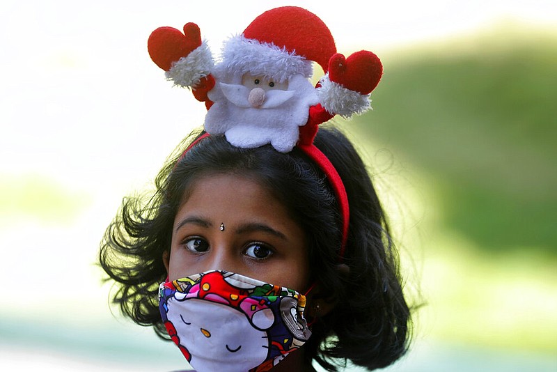 A Sri Lankan Christian girl wears a Santa hair band and a face mask as a precaution against the coronavirus as she arrives at a church to attend the Christmas mass in Colombo, Sri Lanka, Friday, Dec. 25, 2020.