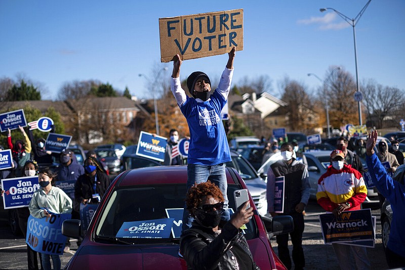 Hamilton Dickey, 8, stands on his mom's car during a rally for Democrats Jon Ossoff and the Rev. Raphael Warnock, both of whom are running to represent Georgia in the U.S. Senate, in Atlanta on Monday, Dec. 14, 2020.