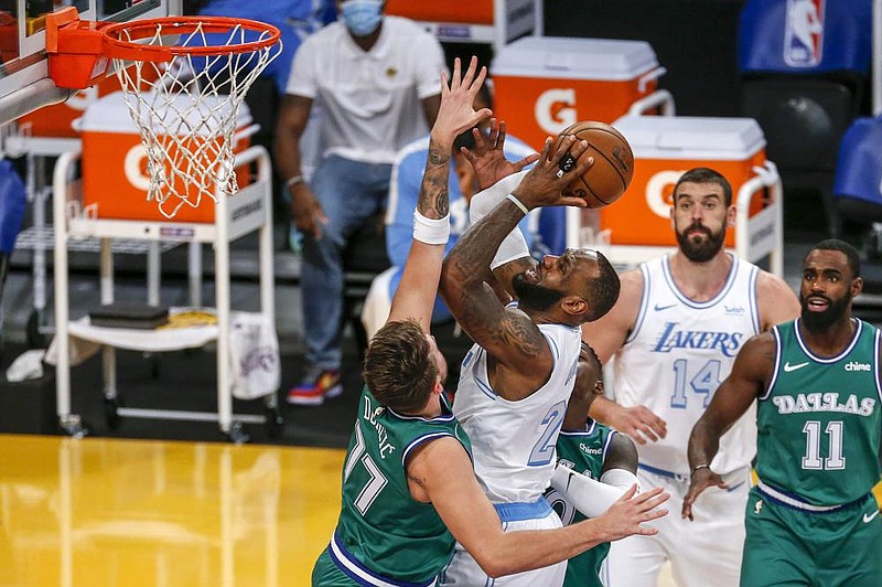 LeBron James (right) goes to the basket while being defended by Luka Doncic of the Dallas Mavericks during the first half Friday in Los Angeles. James scored 22 points to move into second place behind Kobe Bryant for the most points scored on Christmas.
(AP/Ringo H.W. Chiu)