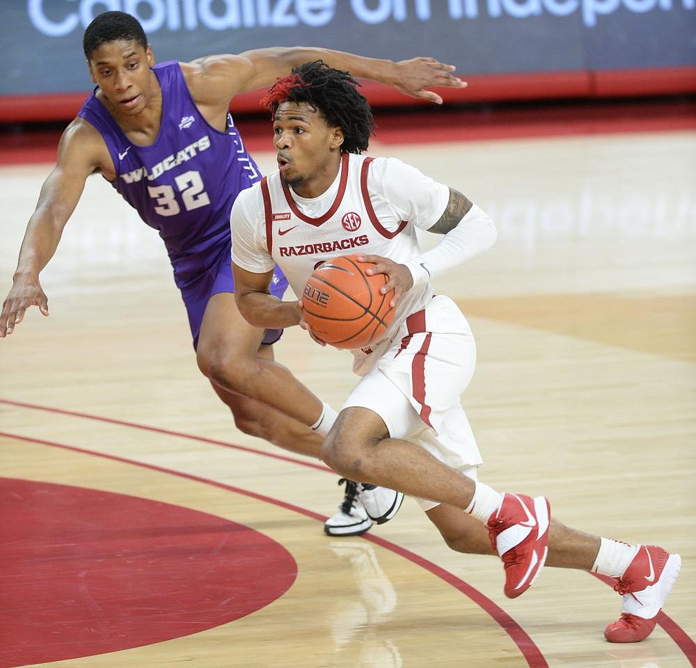 Arkansas guard Desi Sills (right) drives to the lane as he is pursued by Abilene Christian forward Joe Pleasant in the Razorbacks’ 85-72 victory on Tuesday. Sills is the lone returnee to play in every game this season for the Razorbacks, who have managed to get in all eight of their scheduled games — all victories. (NWA Democrat-Gazette/Andy Shupe)