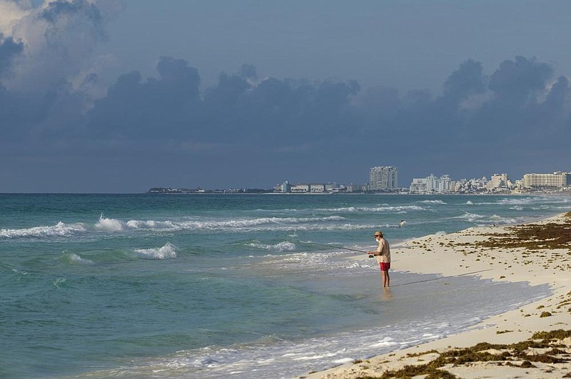 A tourist fishes from the shore in Cancun, Mexico, in mid-June before tourists returned in recent months.
(AP/Victor Ruiz)