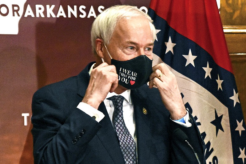 FILE - In this July 20, 2020 file photo, Gov. Asa Hutchinson removes his mask before a briefing at the state capitol in Little Rock. (Staci Vandagriff/The Arkansas Democrat-Gazette)

