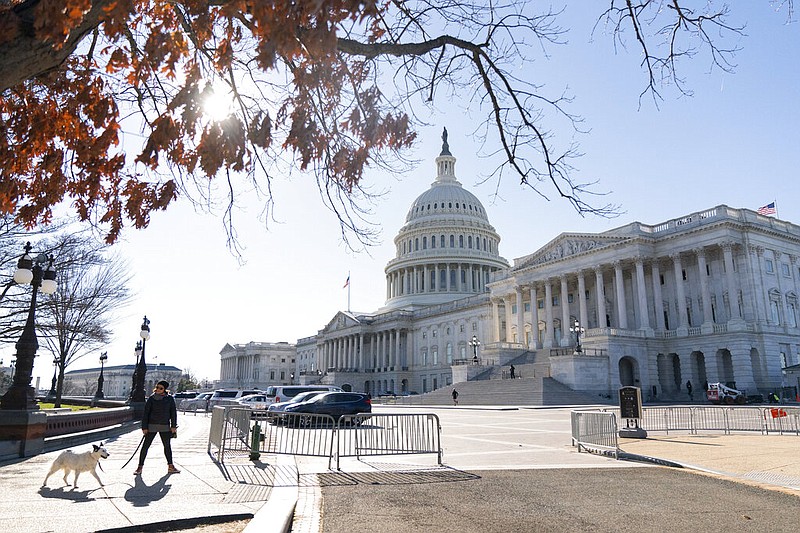 A person walks a dog with the Capitol in the background Tuesday, Dec. 29, 2020, in Washington.