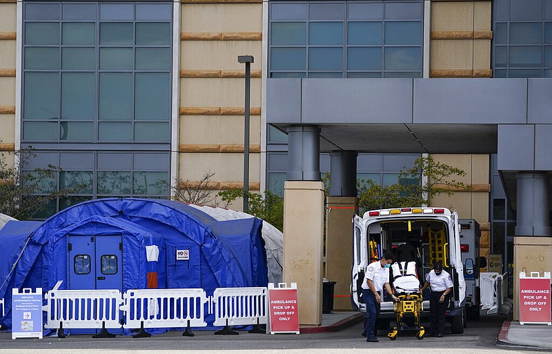 FILE - In this Dec. 17, 2020, file photo, medical workers remove a stretcher from an ambulance near medical tents outside the emergency room at UCI Medical Center, in Irvine, Calif. After months spent tamping down surges and keeping the coronavirus at manageable levels, a variety of factors combined to bring California to a crisis point in the pandemic. (AP Photo/Ashley Landis, File)