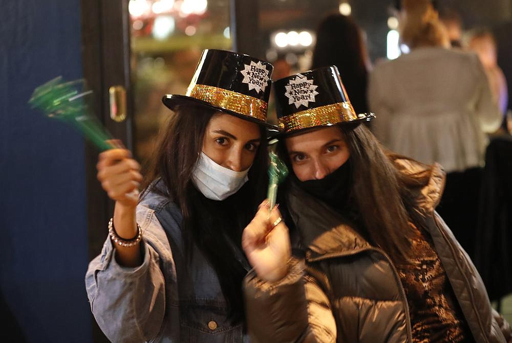 Lebanese women, wearing masks to help prevent spread of the coronavirus, celebrate the New Year outside a pub Thursday in Beirut.
(AP/Hussein Malla)