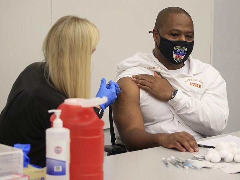 Little Rock Fire Department Battalion Chief Naim Salaam, right, gets a dose of the Pfizer covid vaccine Tuesday Jan. 5, 2021 in Little Rock from Brittany Marsh, pharmacist and owner at the Cornerstone Pharmacy on Rodney Parham Road, as the first Little Rock fire and police department personnel got vaccinations. See more photos at arkansasonline.com/16vaccine/. (Arkansas Democrat-Gazette/Staton Breidenthal)