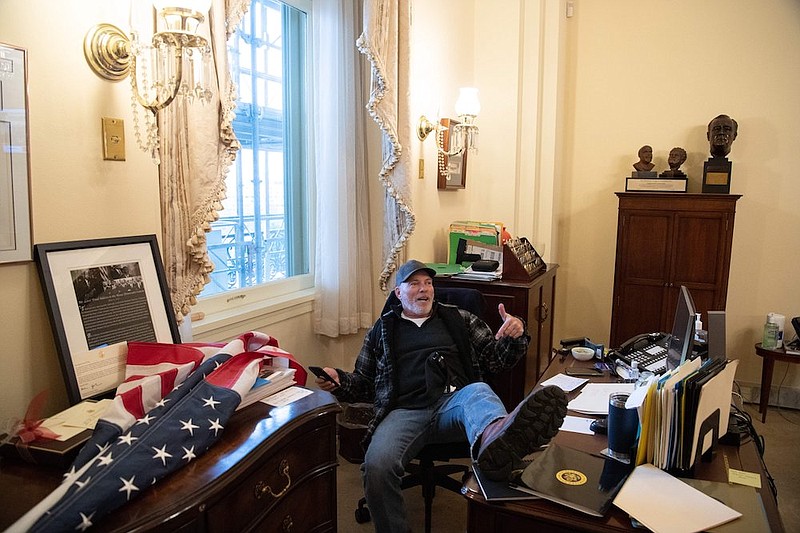 Special to the Arkansas Democrat Gazette - A supporter of U.S. President Donald Trump sits inside the office of U.S. Speaker of the House Nancy Pelosi as he protests inside the U.S. Capitol in Washington, D.C., Jan. 6, 2021. - Demonstrators breeched security and entered the Capitol as Congress debated the a 2020 presidential election Electoral Vote Certification. (Photo by SAUL LOEB/AFP via Getty Images)
