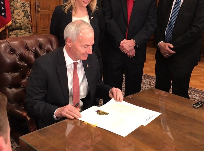 Gov. Asa Hutchinson signs an executive order in this 2018 file photo.