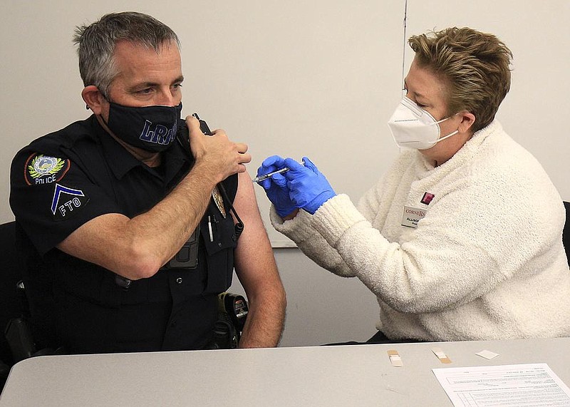 Little Rock Police Officer Timothy Pope, left, gets a dose of the Pfizer covid vaccine Tuesday Jan. 5, 2021 in Little Rock from pharmacist Allison Ingram with Cornerstone Pharmacy on Rodney Parham Road as the first Little Rock fire and police department personnel got vaccinations. See more photos at arkansasonline.com/16vaccine/.