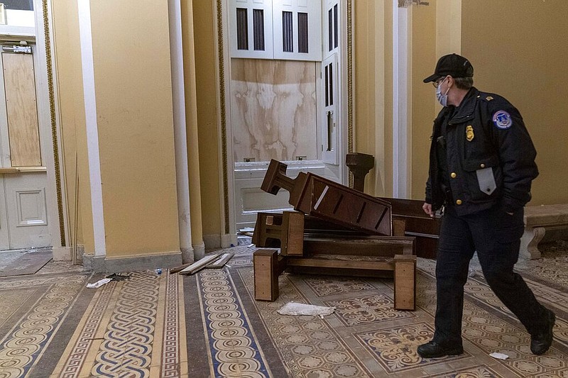 A U.S. Capitol Police officer walks past damage at the Capitol in Washington in the early morning hours of Thursday, Jan. 7, 2021, after protesters stormed the Capitol on Wednesday.