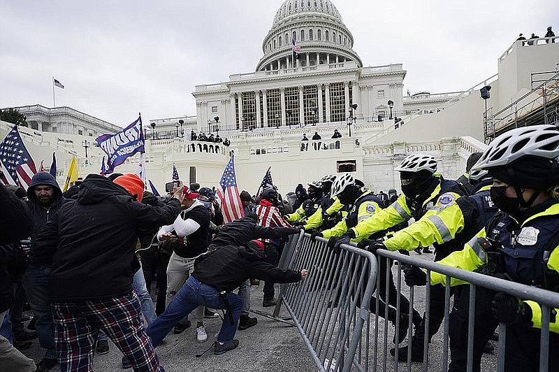 President Donald Trump’s supporters (left) try to break through a police barrier Wednesday at the U.S. Capitol in a scene of chaos that put a stop to House and Senate action and left a woman dead. (AP/Julio Cortez)
story.lead_photo.caption